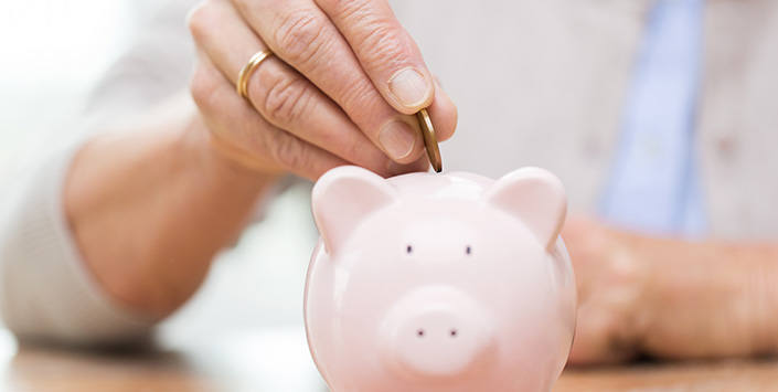 Person putting money into a piggy bank.