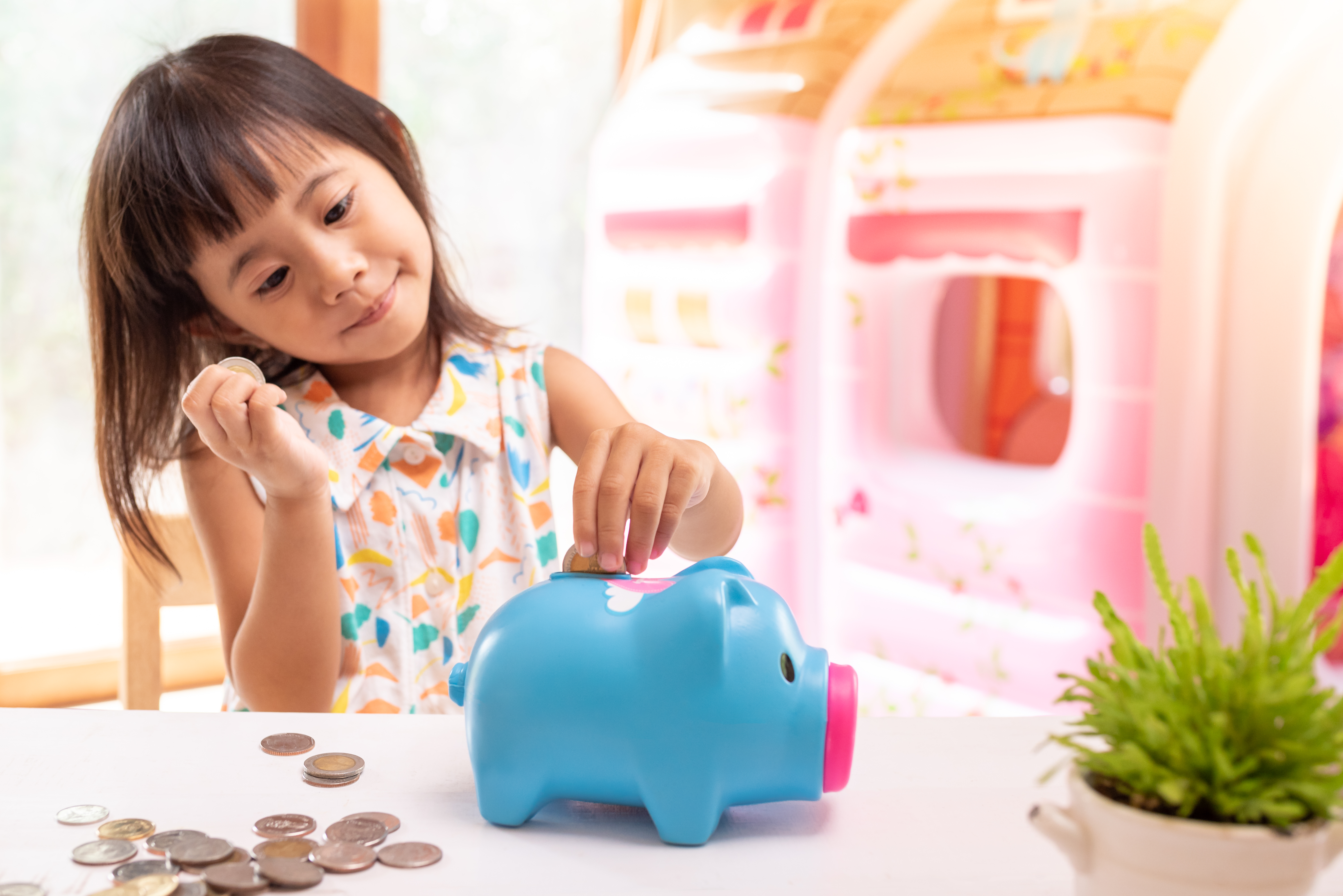 Female child putting money in blue piggy bank